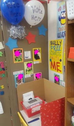 Corner with brightly colored posters and two ballons that say Vote Here