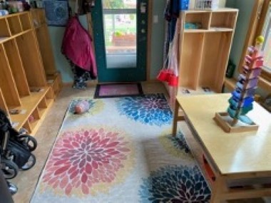 Classroom with wood table and wood lockers with a view of the front door