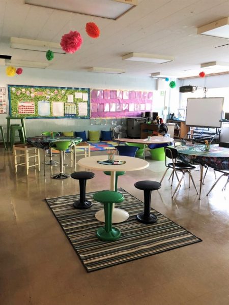 Classroom with different types of seating areas. In the foreground is a circular table with four stools.