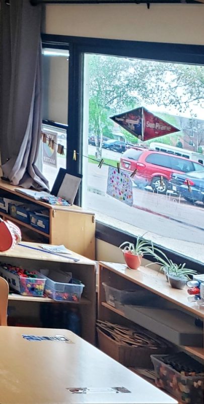 View from within the classroom looking out a window into the parking lot. The window has a Sun Prairie decal on it.